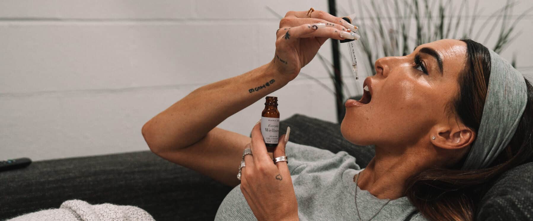 a person holding a dropper with cannabis tincture under their tongue.