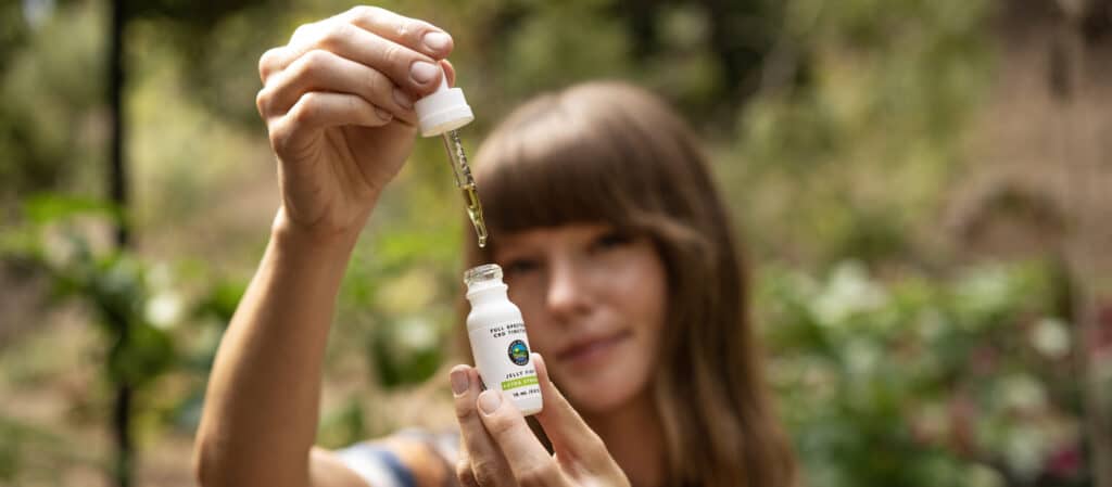 a woman holding a cannabis tincture bottle. 