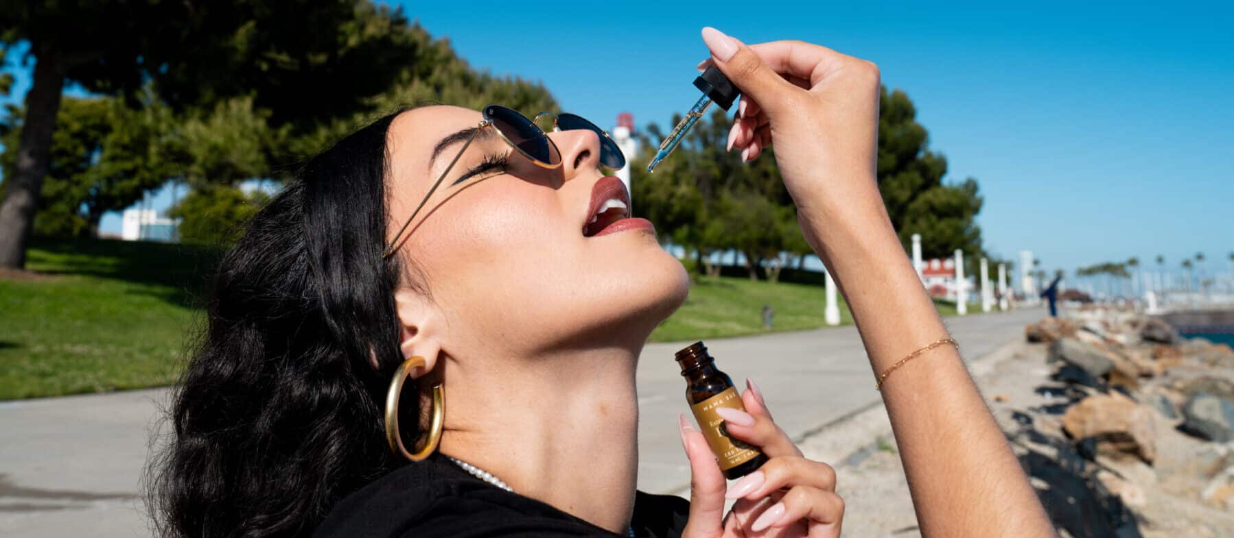 a woman delicately places cannabis tincture on her tongue.